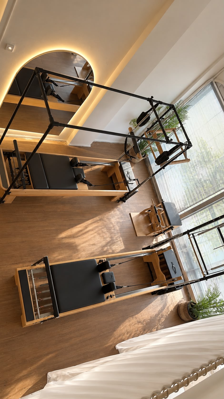 Focus & Flow Studio Buca — ışıklı kemerli ayna, cadillac ve reformer aletleriyle gün ışığı alan stüdyo salonu
